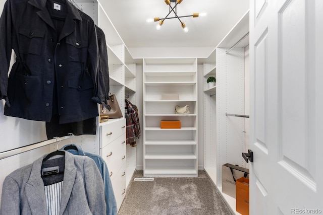 walk in closet featuring carpet floors and an inviting chandelier