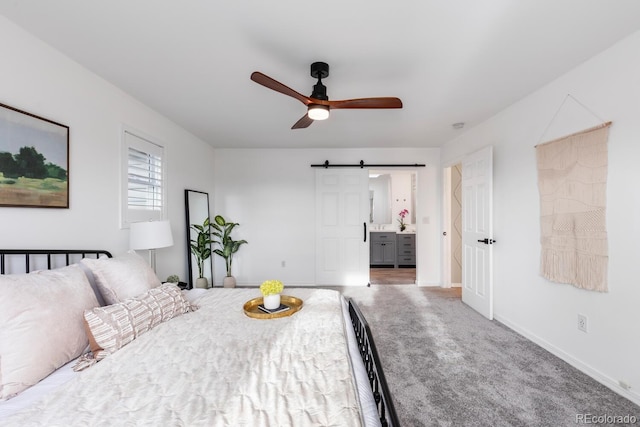 bedroom with a barn door, baseboards, carpet, and ensuite bath