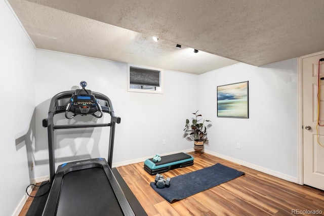 exercise room with a textured ceiling, baseboards, and wood finished floors