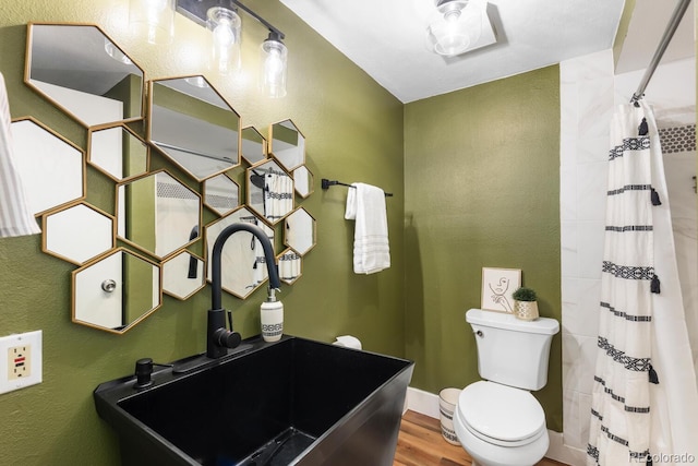 bathroom with wood finished floors, curtained shower, toilet, and a sink