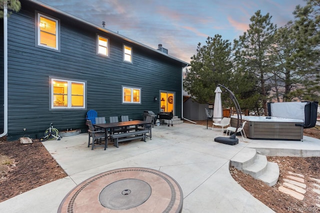 patio terrace at dusk with outdoor dining space and a hot tub