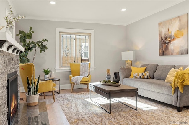 living room with a stone fireplace, hardwood / wood-style floors, and ornamental molding