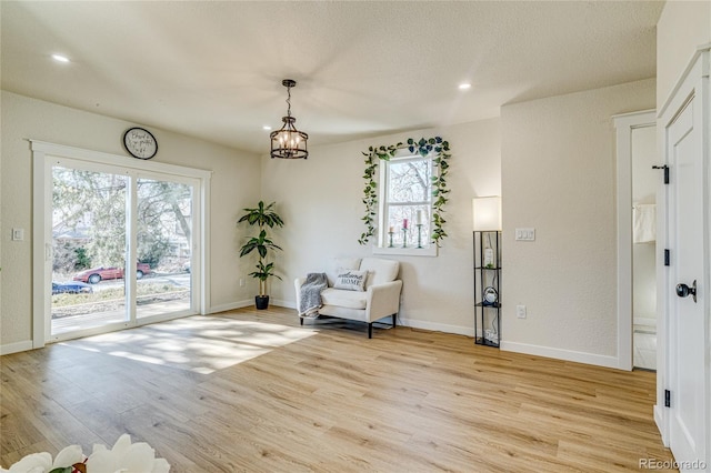 living area featuring light wood finished floors, recessed lighting, baseboards, and a notable chandelier