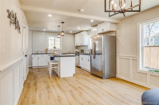 kitchen featuring dark countertops, appliances with stainless steel finishes, a sink, and light wood-type flooring