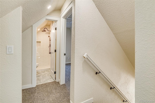 hallway featuring a textured wall and carpet floors