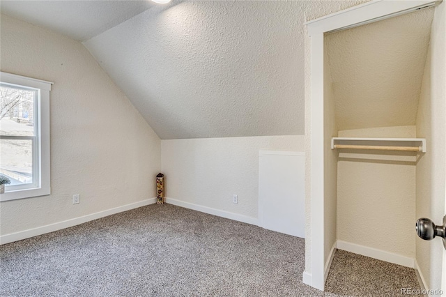 bonus room with lofted ceiling, a textured ceiling, baseboards, and carpet