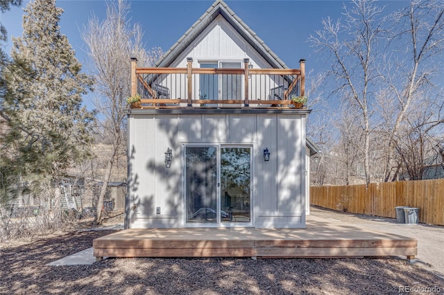 rear view of house with a balcony, a wooden deck, and fence