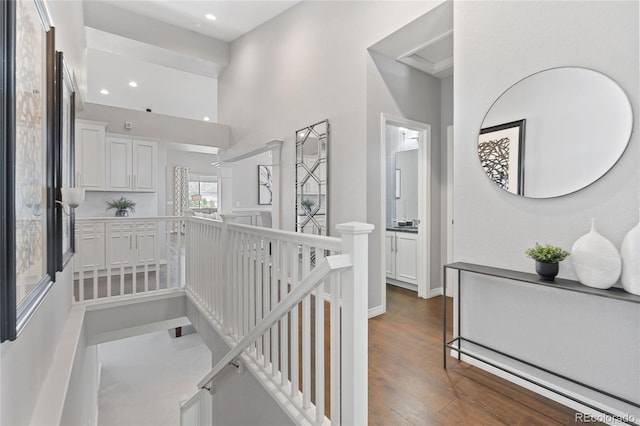 corridor featuring dark wood-style floors, recessed lighting, a high ceiling, an upstairs landing, and baseboards