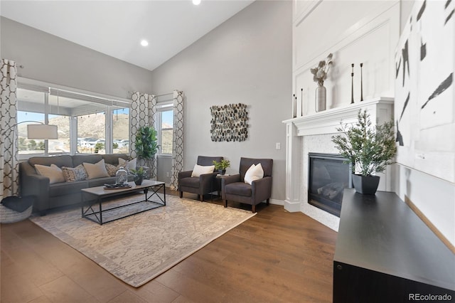 living area with high vaulted ceiling, recessed lighting, a fireplace, baseboards, and dark wood finished floors