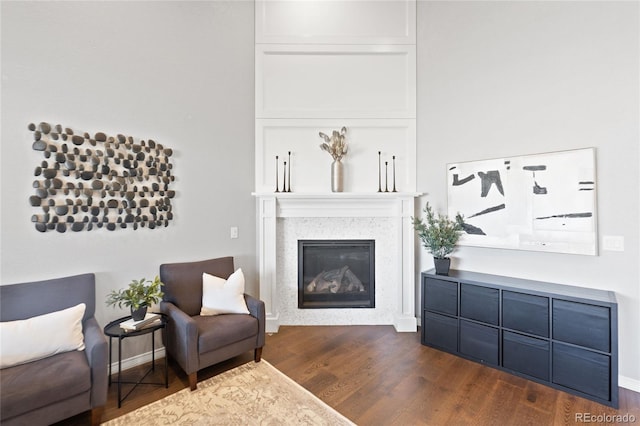 living area featuring a glass covered fireplace, dark wood finished floors, and baseboards