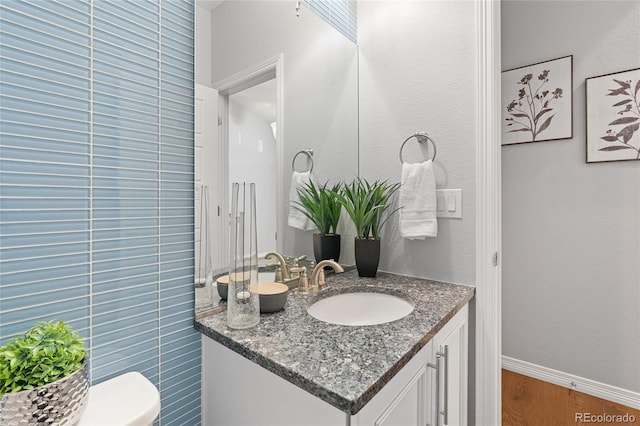 bathroom with toilet, baseboards, wood finished floors, and vanity