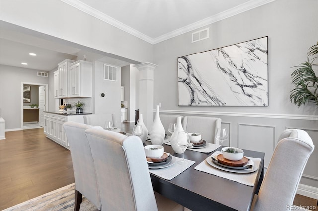 dining room with visible vents, decorative columns, and wood finished floors