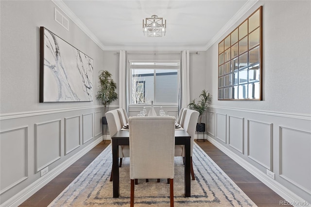 dining space featuring crown molding, dark wood finished floors, visible vents, and a decorative wall