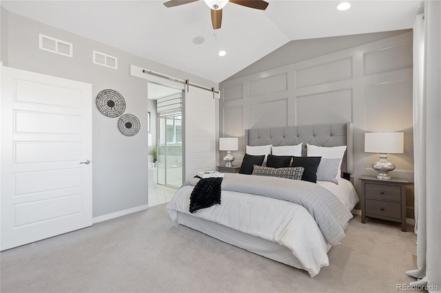 bedroom with light carpet, a barn door, visible vents, and a decorative wall