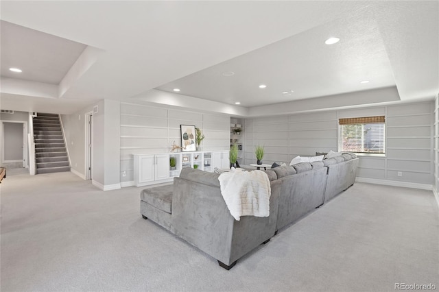 living area featuring baseboards, light colored carpet, stairway, a tray ceiling, and recessed lighting