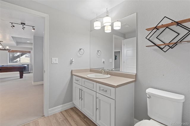 bathroom featuring toilet, vanity, wood finished floors, billiards, and baseboards