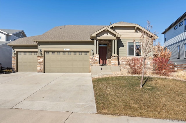 craftsman inspired home featuring roof with shingles, concrete driveway, an attached garage, a front yard, and stone siding