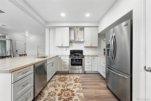 10010 E Gunnison Pl Unit 707, Aurora, CO 80247 - kitchen featuring appliances with stainless steel finishes, wall chimney range hood, a sink, a peninsula, and butcher block countertops