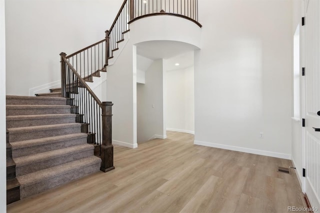 stairs featuring a high ceiling and hardwood / wood-style flooring