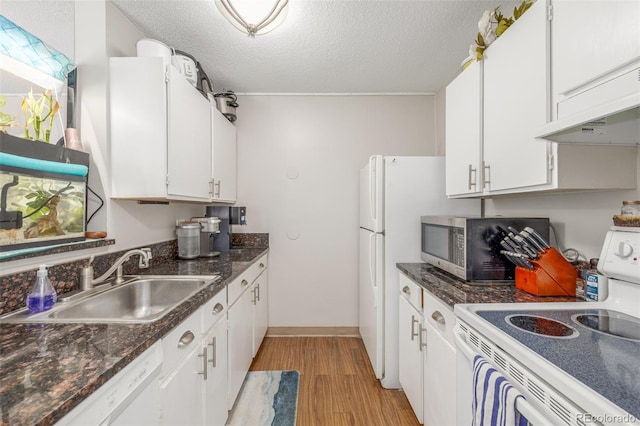 kitchen with white appliances, light wood-style floors, white cabinets, and a sink