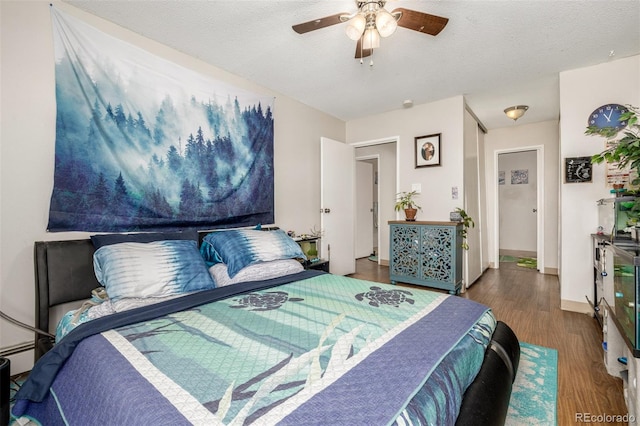 bedroom with dark wood finished floors, a textured ceiling, baseboards, and ceiling fan