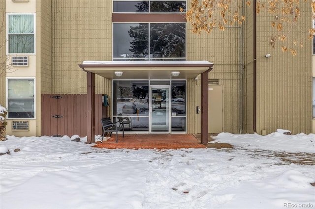 snow covered property entrance with fence