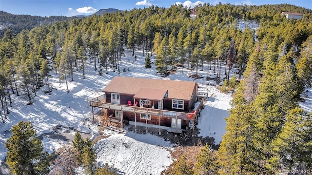 snowy aerial view featuring a forest view