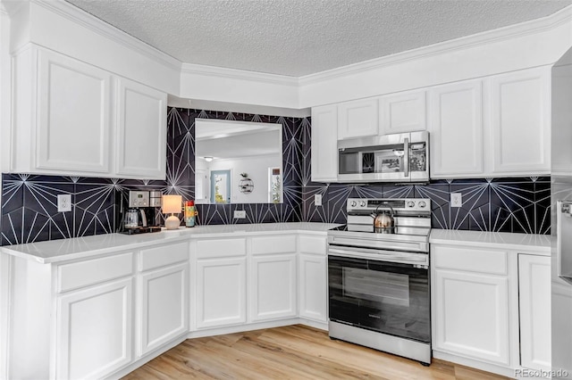 kitchen with light wood-style flooring, stainless steel appliances, white cabinets, a textured ceiling, and tasteful backsplash