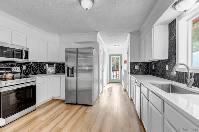 kitchen featuring a sink, appliances with stainless steel finishes, light wood-style flooring, and light countertops