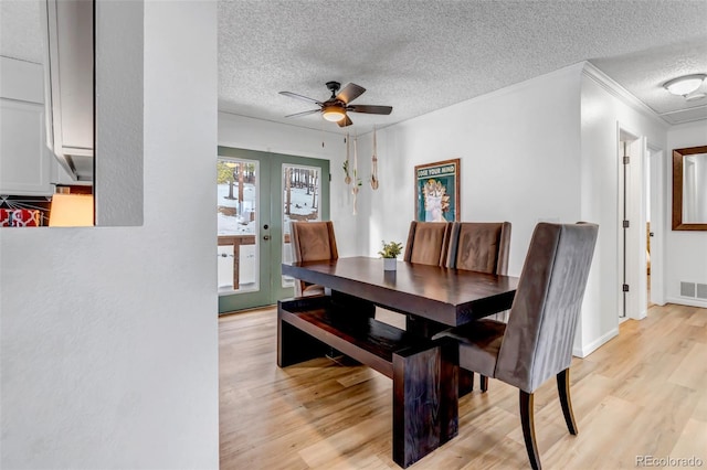 dining space featuring visible vents, crown molding, french doors, light wood-style floors, and a textured ceiling