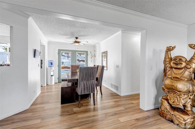 dining area with crown molding, light wood-style flooring, and visible vents