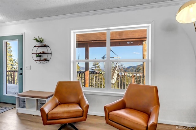 living area featuring a textured ceiling, crown molding, baseboards, and wood finished floors