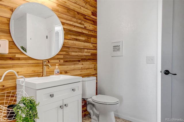 half bath featuring vanity, wooden walls, and toilet