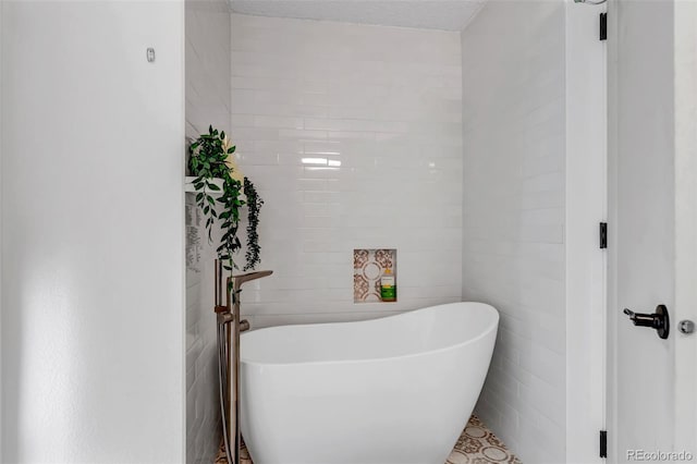 full bathroom featuring a soaking tub, tile walls, and a textured ceiling