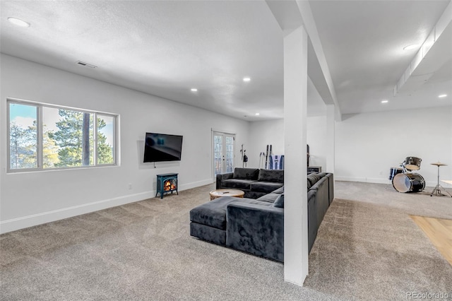 living room with a wealth of natural light, visible vents, carpet floors, and baseboards