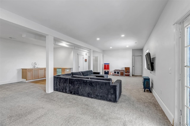 carpeted living room with wet bar, recessed lighting, baseboards, and a sink