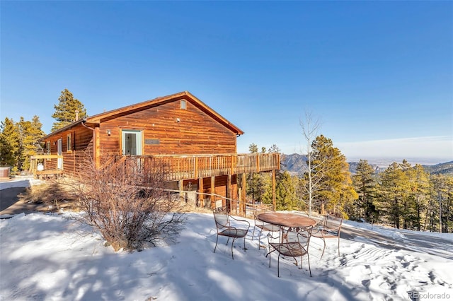 snow covered rear of property with a deck