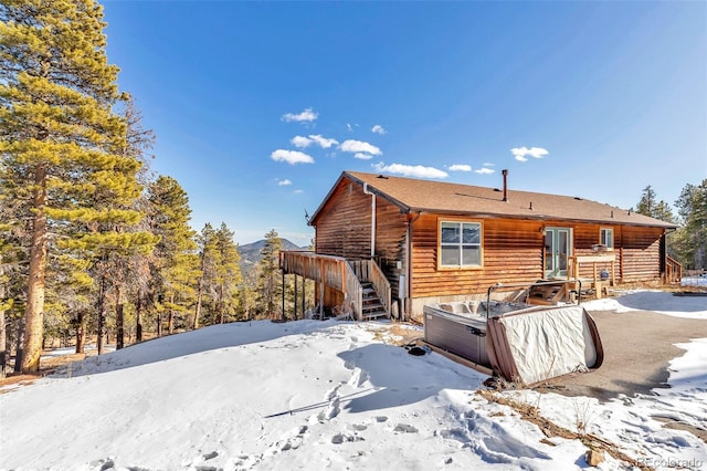 snow covered property with stairs and a deck