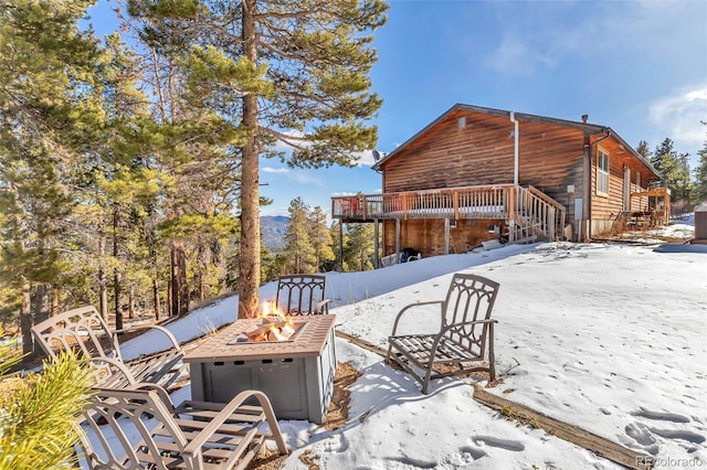 snow covered patio with a deck and an outdoor fire pit