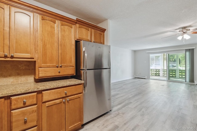 kitchen featuring ceiling fan, light hardwood / wood-style floors, a textured ceiling, baseboard heating, and stainless steel fridge