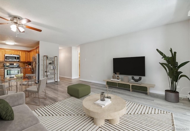 living room featuring a textured ceiling, ceiling fan, and light hardwood / wood-style flooring