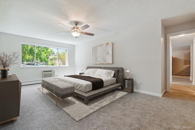 bedroom featuring ceiling fan, carpet, an AC wall unit, a baseboard heating unit, and a textured ceiling