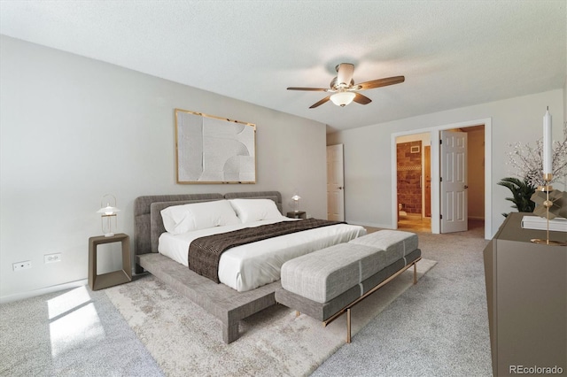 bedroom with light carpet, ceiling fan, ensuite bathroom, and a textured ceiling