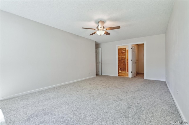 unfurnished bedroom with a spacious closet, a textured ceiling, carpet flooring, ceiling fan, and ensuite bathroom