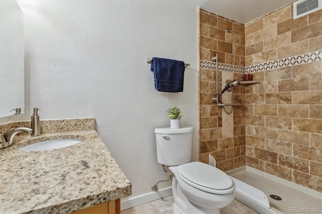 bathroom featuring toilet, vanity, and tiled shower