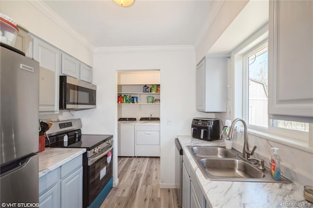 2080 E 84th Ave, Denver, CO 80229 - kitchen with appliances with stainless steel finishes, separate washer and dryer, a sink, light wood-style floors, and ornamental molding