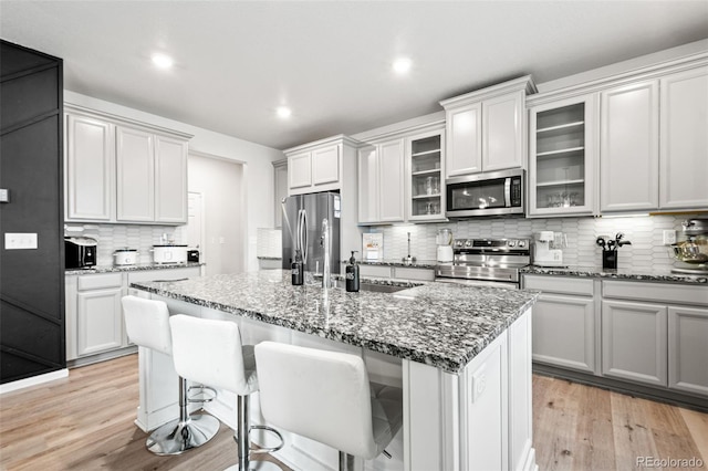 3074 Kestrel St, Brighton, CO 80601 - kitchen with stainless steel appliances, tasteful backsplash, dark stone countertops, a kitchen breakfast bar, and a center island with sink