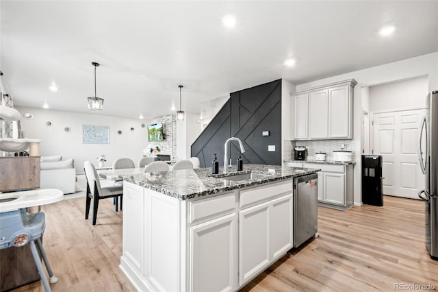 3074 Kestrel St, Brighton, CO 80601 - kitchen featuring appliances with stainless steel finishes, light wood-type flooring, dark stone countertops, open floor plan, and recessed lighting