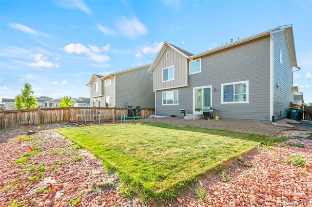 3074 Kestrel St, Brighton, CO 80601 - back of house with a trampoline, a fenced backyard, and board and batten siding