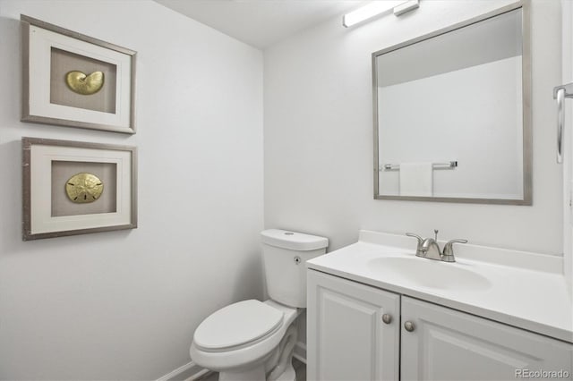 bathroom featuring toilet, vanity, and baseboards